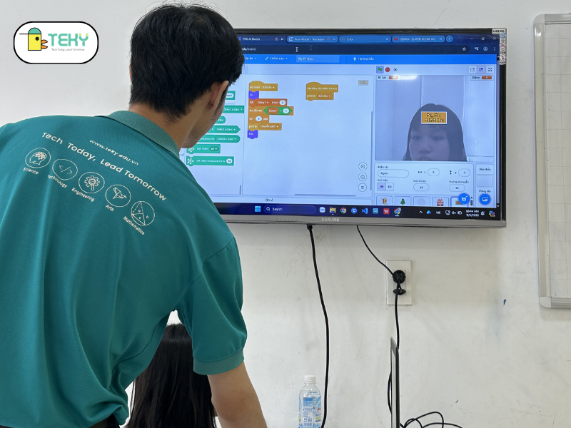 Thầy giáo hướng dẫn con sử dụng AI nhận diện gương mặt.